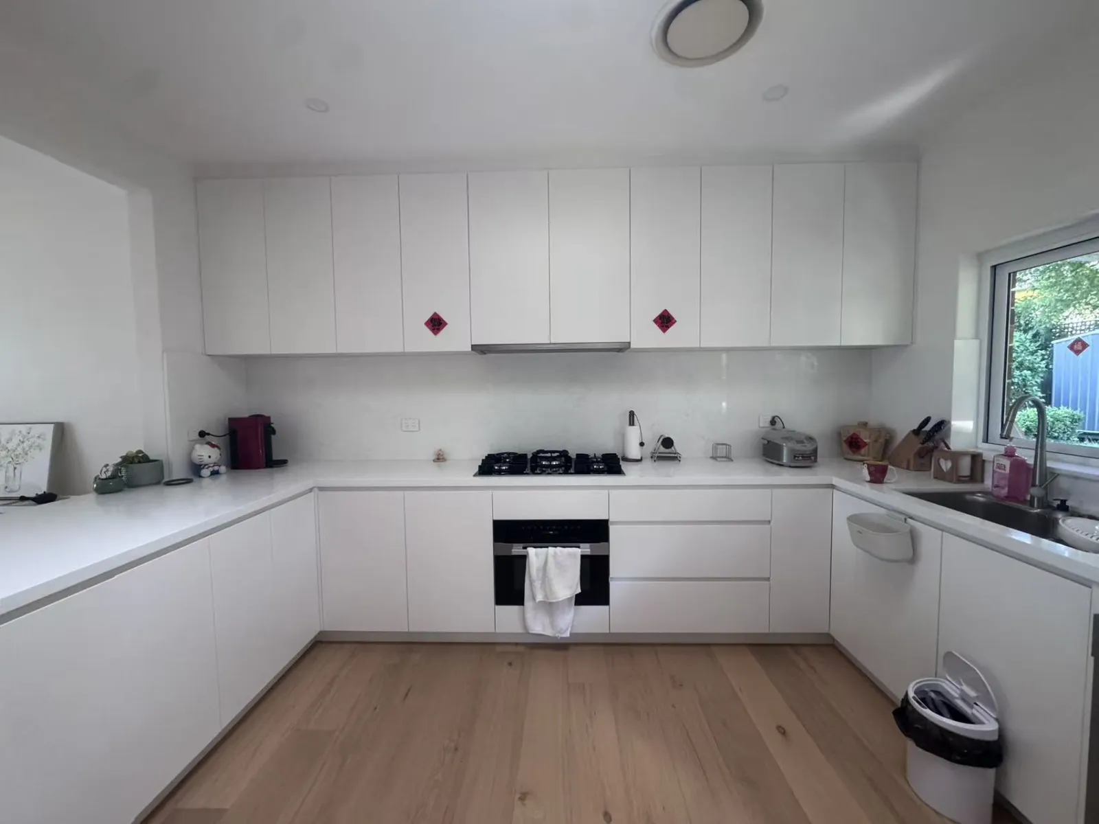 Completed Turramurra kitchen with white U-shaped cabinetry, benchtops, gas cooktop and timber flooring