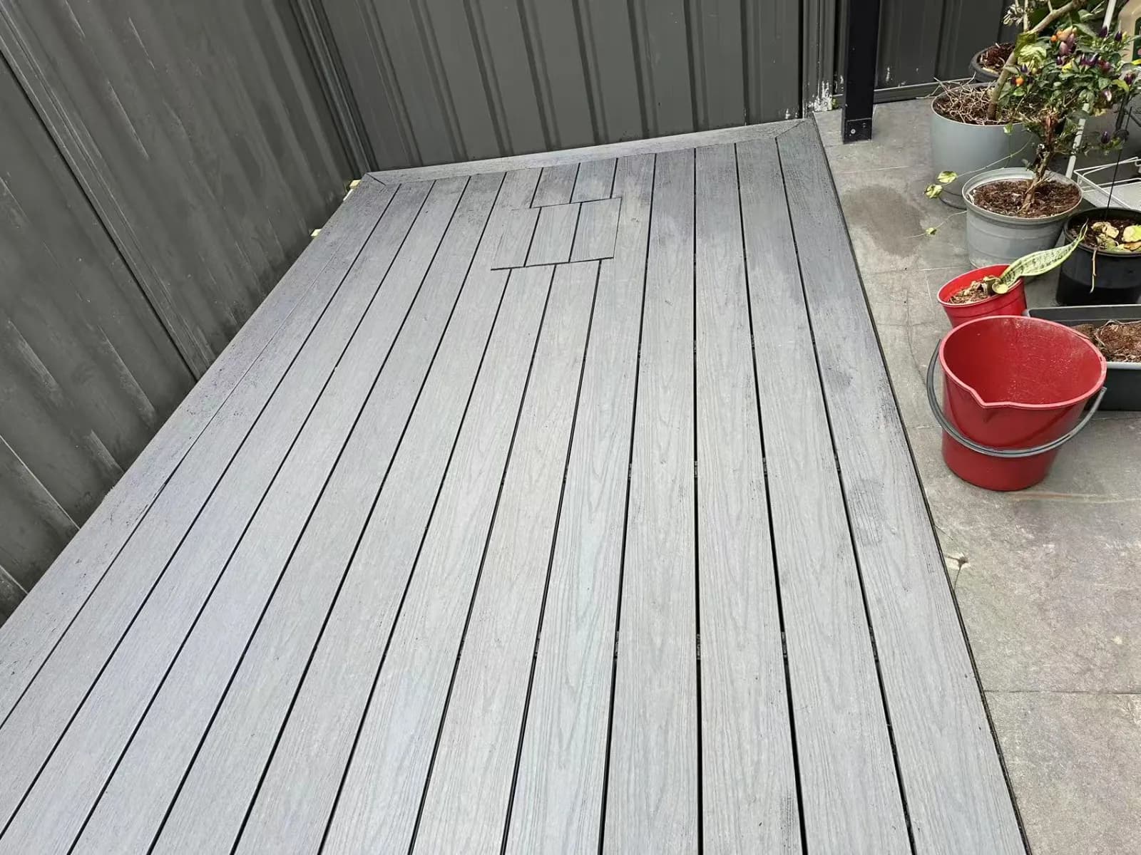 Completed grey deck in a Dundas courtyard, beside metal fencing and pot plants